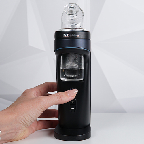 Dr. Dabber Switch 2 sur une table pendant qu'une femme appuie sur le bouton d'alimentation