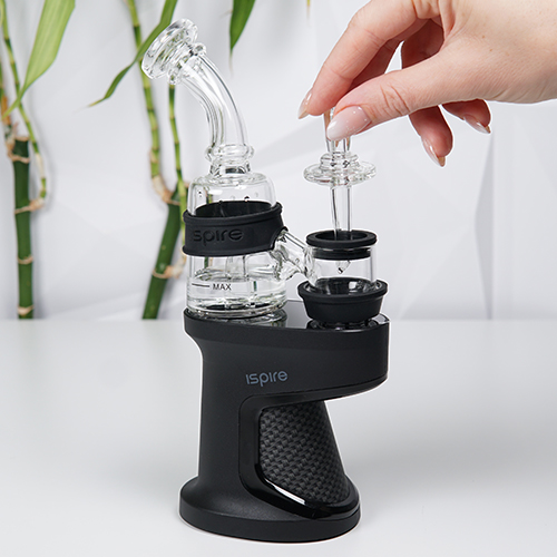 Ispire Daab Kit sur une table pendant qu'une femme tient un carb cap en verre près de la chambre de chauffe