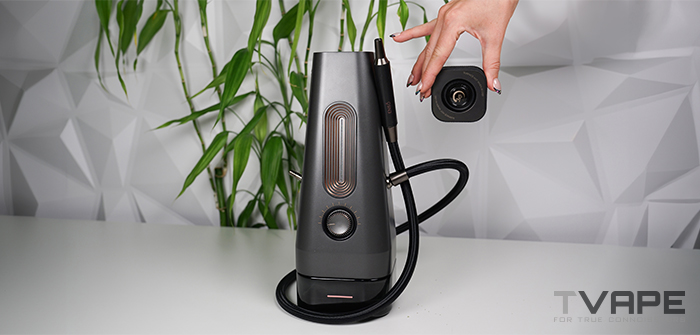 On retire à la main le couvercle amovible « Glass ThermoCap » de la chicha électrique AirVape Enso 2026, ce qui permet de voir la chambre de chauffe ouverte et le tuyau à vapeur qui y est raccordé